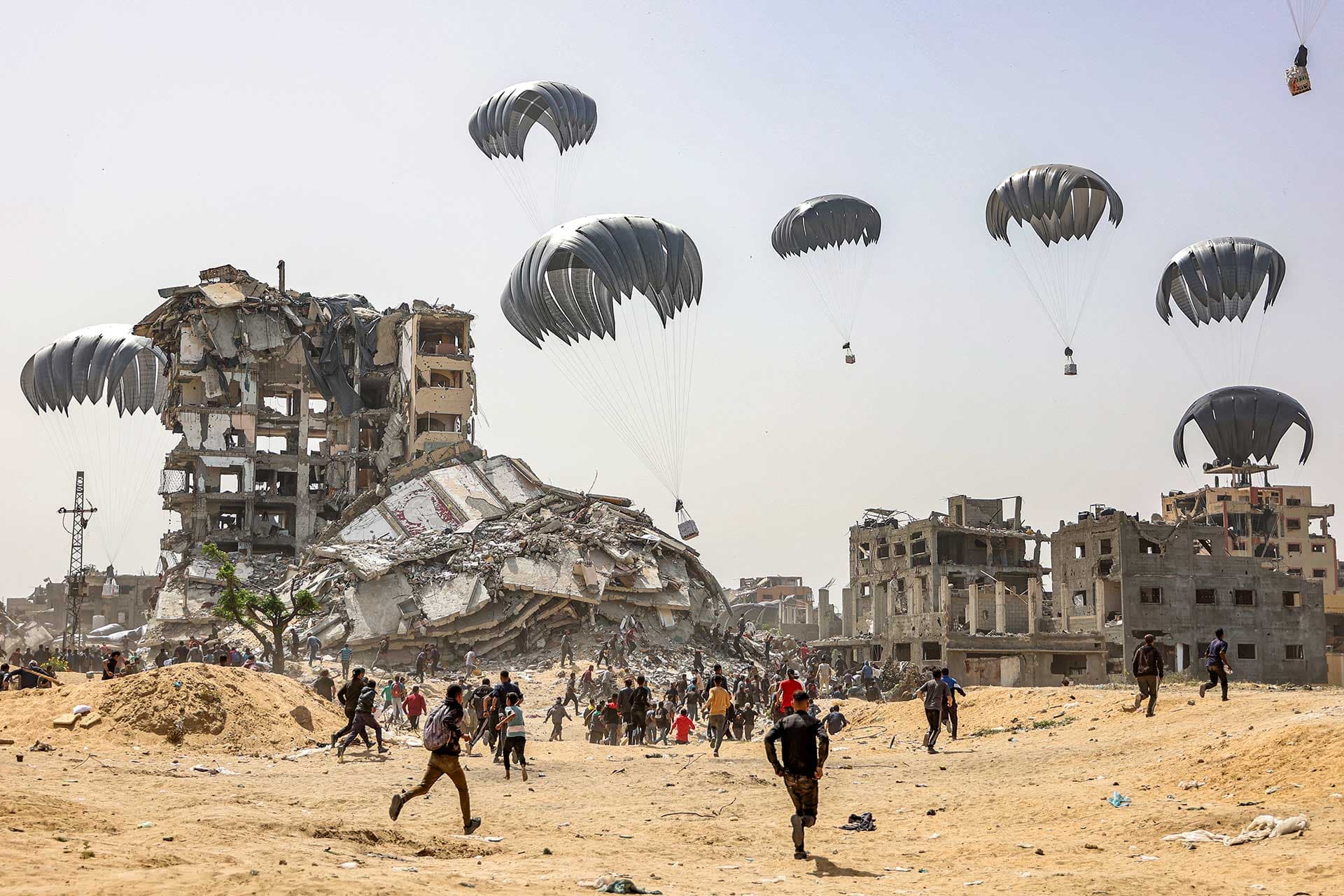 Personas corren para alcanzar los paquetes de ayuda humanitaria en la Franja de Gaza