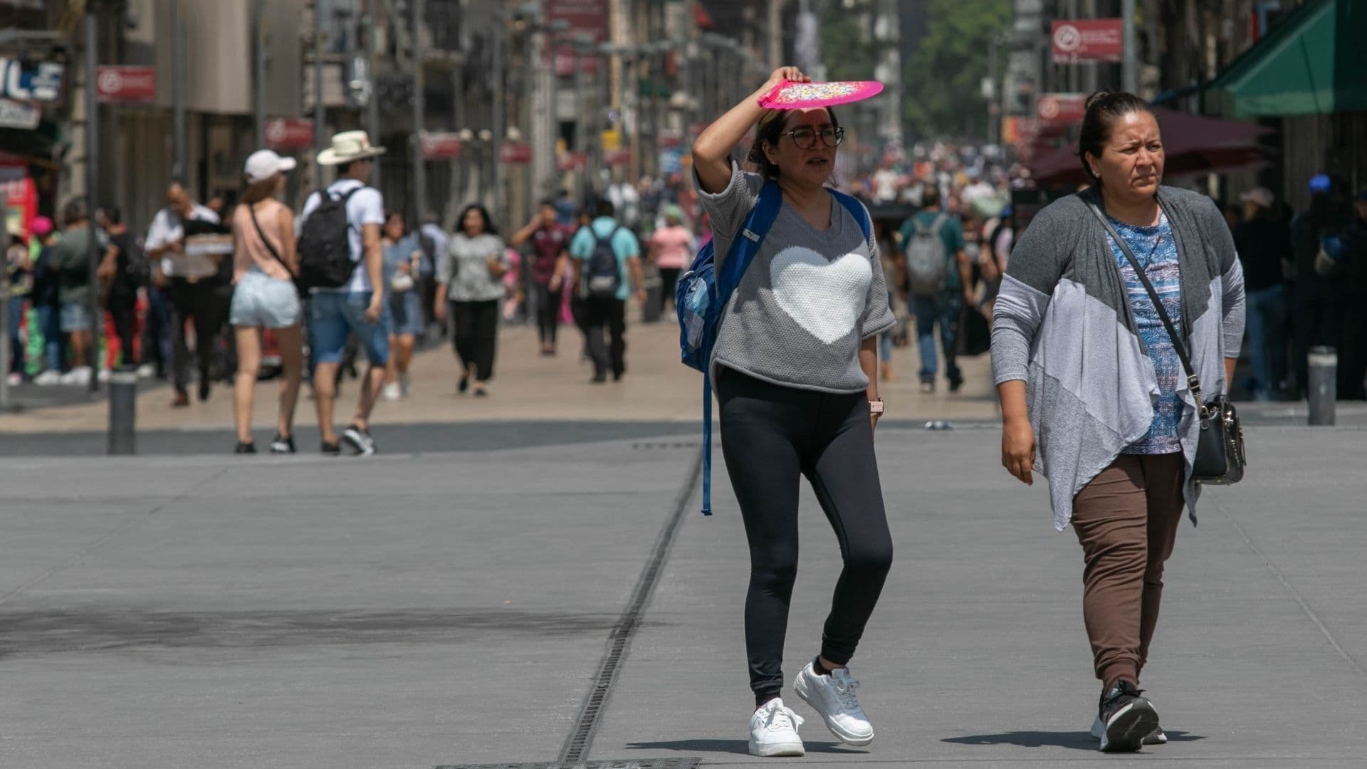 Dos personas caminan bajo el sol en medio de una ola de calor en la CDMX