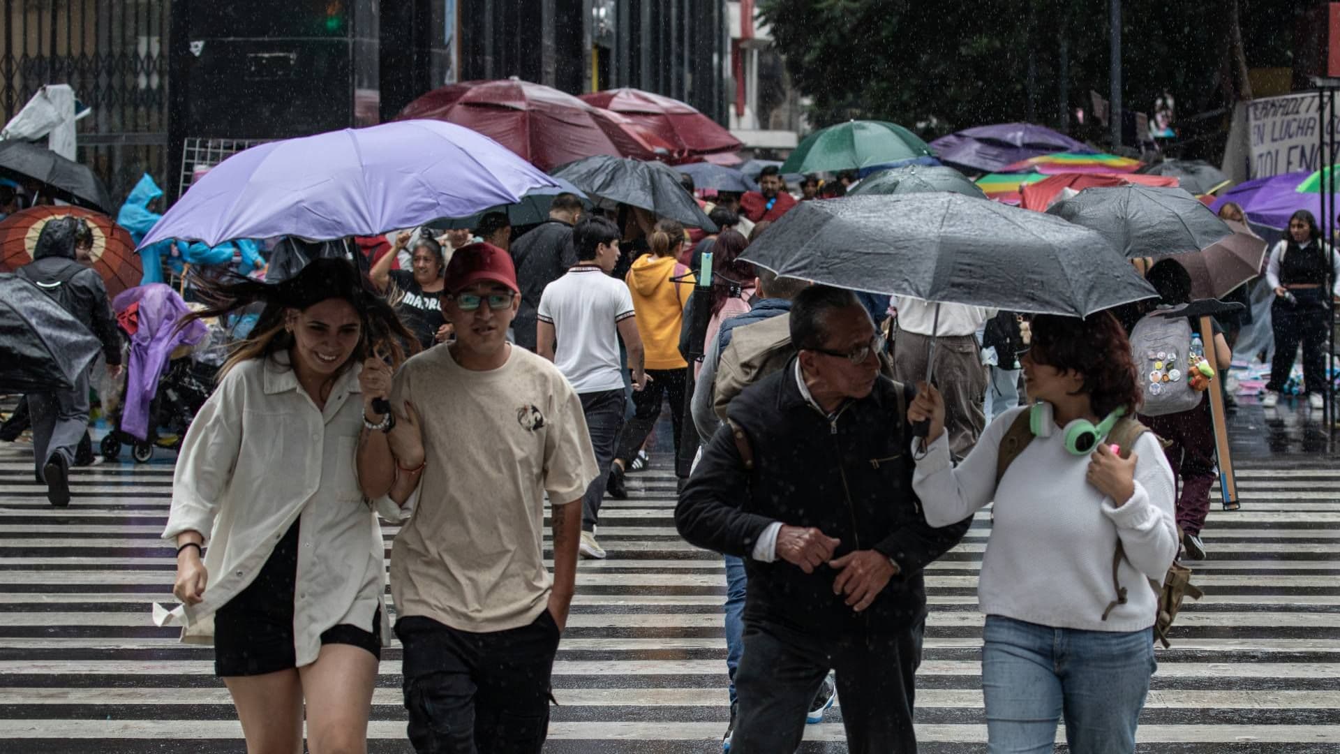 Personas se protegen de la lluvia con paraguas en CDMX.